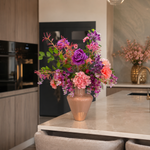 Zijden boeket Amélien met roze en paarse bloemen in taupe vaas op modern kookeiland
