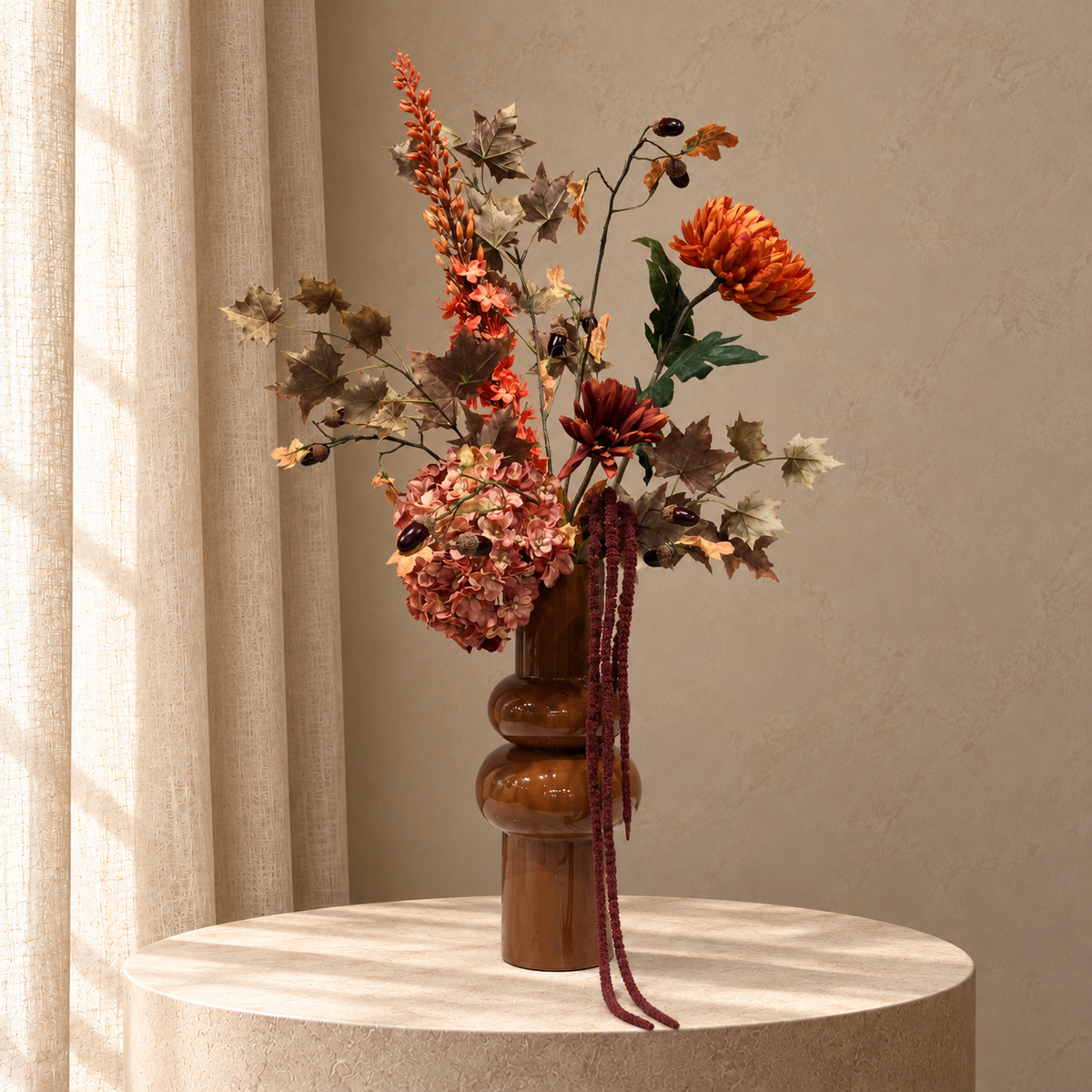 Zijden herfstboeket Caramel Harvest met oranje bloemen, roze hortensia, bruin blad en bordeaux hangende takken in karamelkleurige vaas op beige studioachtergrond