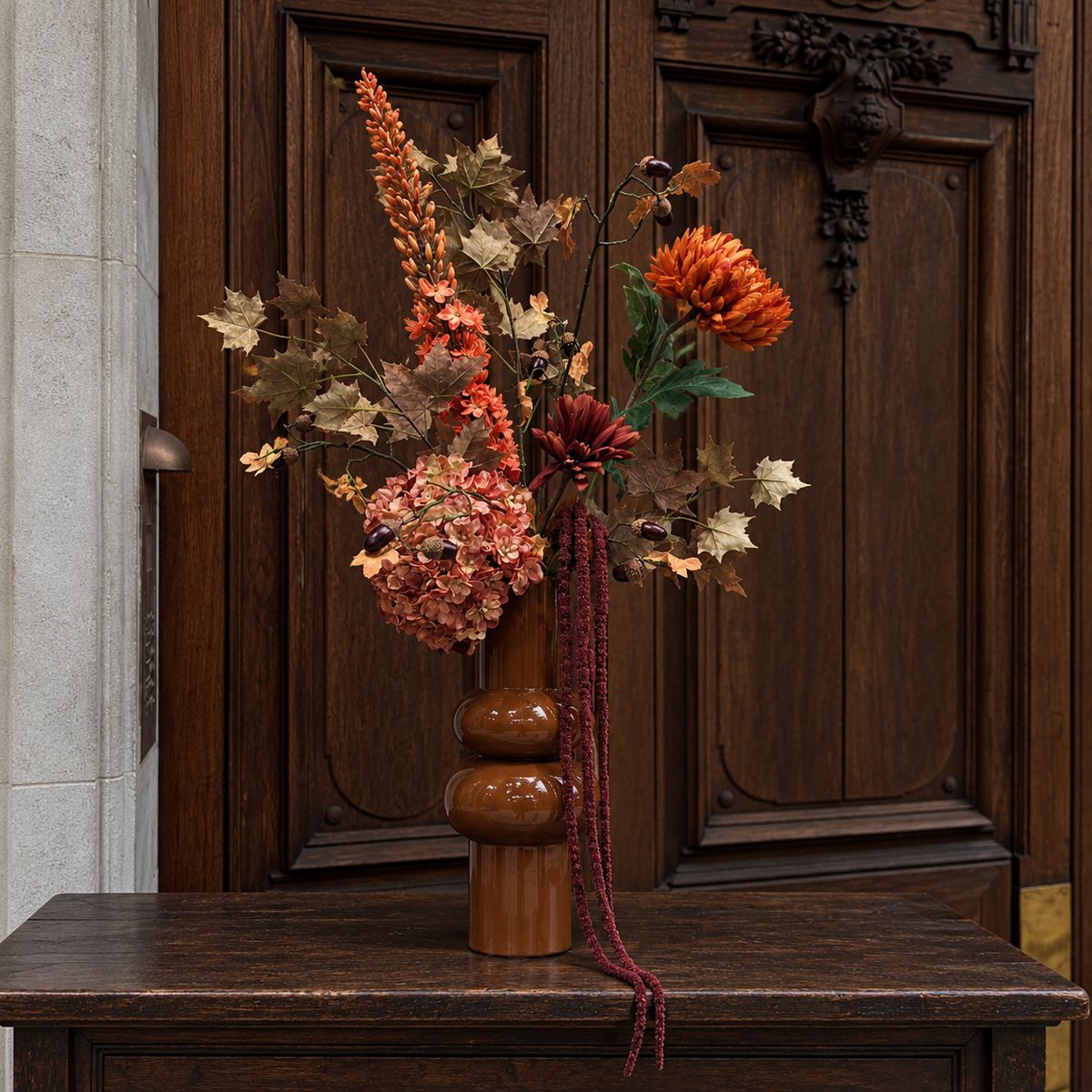 Caramel Harvest in karamelkleurige vaas op een houten tafel voor een donkere houten deur
