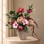 Zijden boeket Winter Blush in roze, crème en bordeaux met wintergroen in een matte taupekleurige vaas op beige studioachtergrond