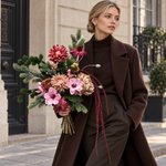 Blond model houdt zijden boeket Winter Blush met roze bloemen, wintergroen en bordeaux hangende takken zonder vaas vast